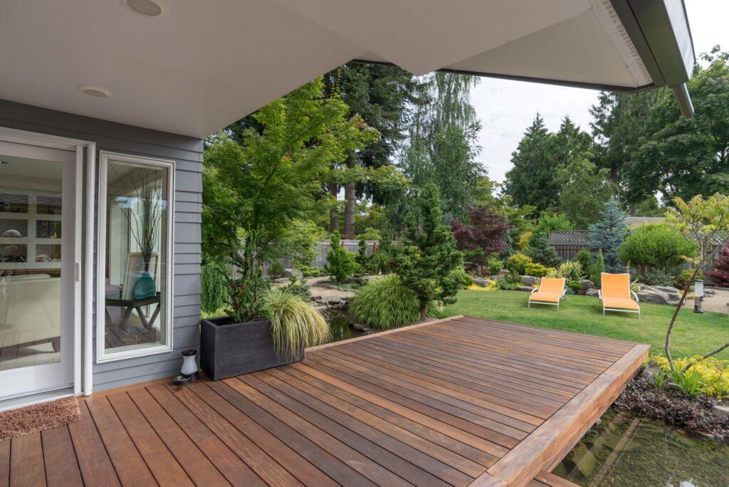 Holzterrasse mit Blick auf einen gepflegten Garten und Teich